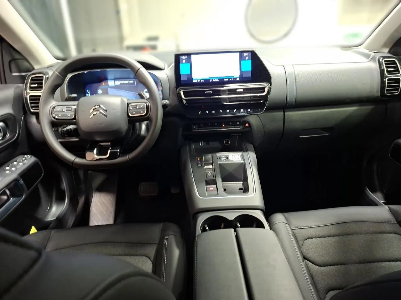 Vue intérieure avant de la Citroën C5 Aircross 2025, tableau de bord noir avec écran tactile et volant multifonction.