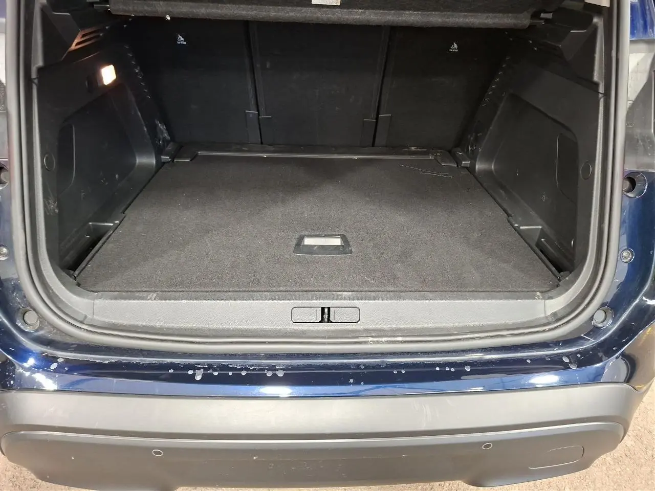 Coffre ouvert vu de l'arrière d'un Citroën C5 Aircross Bleu Eclipse avec plancher plat et garnitures noires.