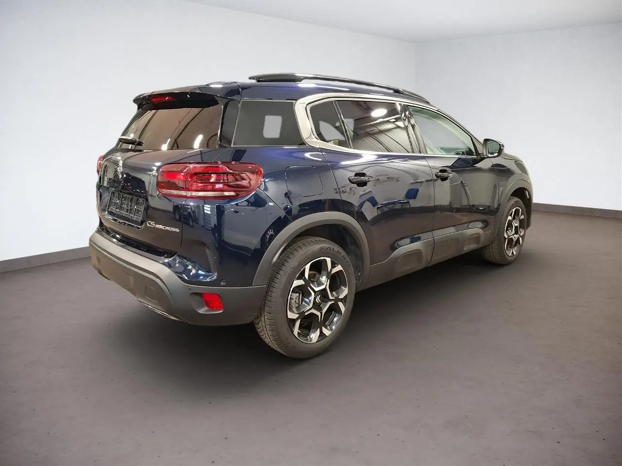 Vue 3/4 arrière droit d'un Citroën C5 Aircross Bleu Eclipse avec jantes alliage bi-ton et barres de toit noires.