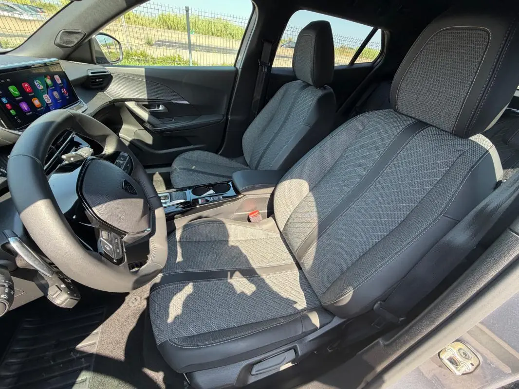 Intérieur gris du Peugeot 2008 Hybrid 145 Allure 2025, vue côté conducteur avec sièges tissu et tableau de bord digital.