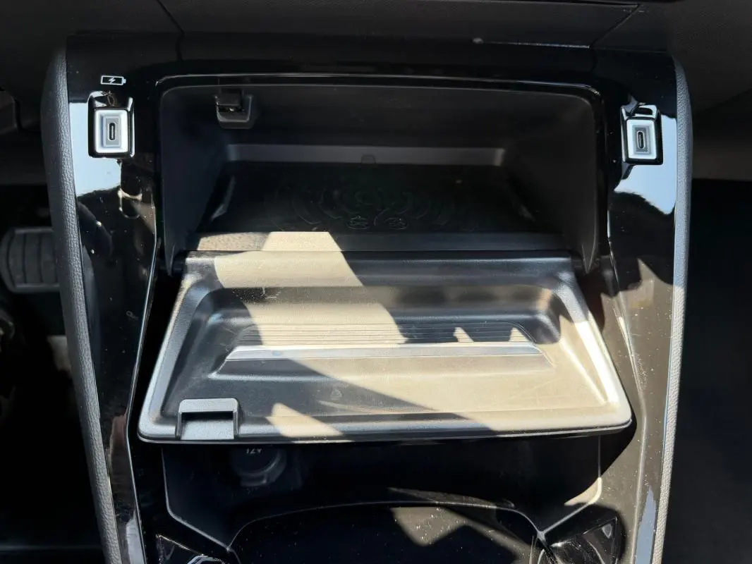 Gros plan sur la console centrale noire du Peugeot 2008 Hybrid 145 e-DCS6 Allure 2025 avec compartiment ouvert et ports USB visibles.