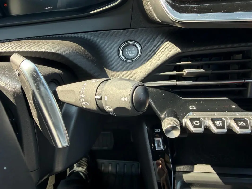 Détail intérieur du tableau de bord du Peugeot 2008 Hybrid 145 e-DCS6 Allure 2025, avec bouton start/stop et commande de clignotants.