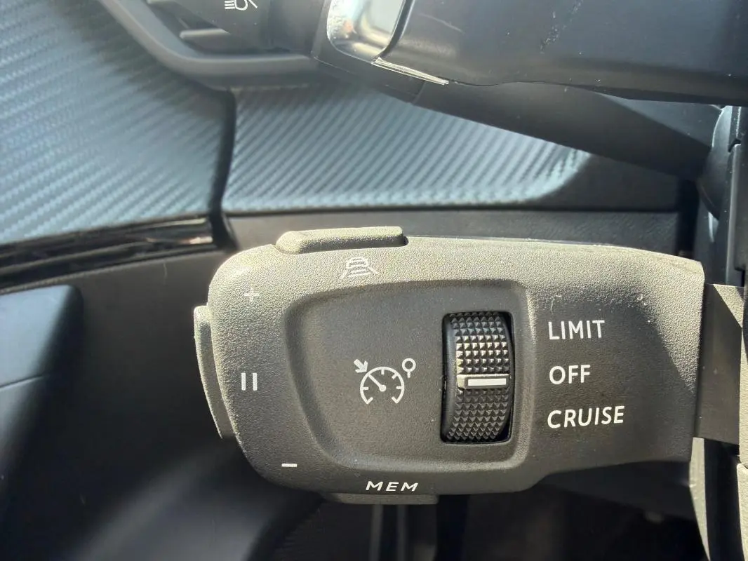 Gros plan sur la commande de régulateur de vitesse du Peugeot 2008 Hybrid 145 e-DCS6 Allure gris, intérieur.
