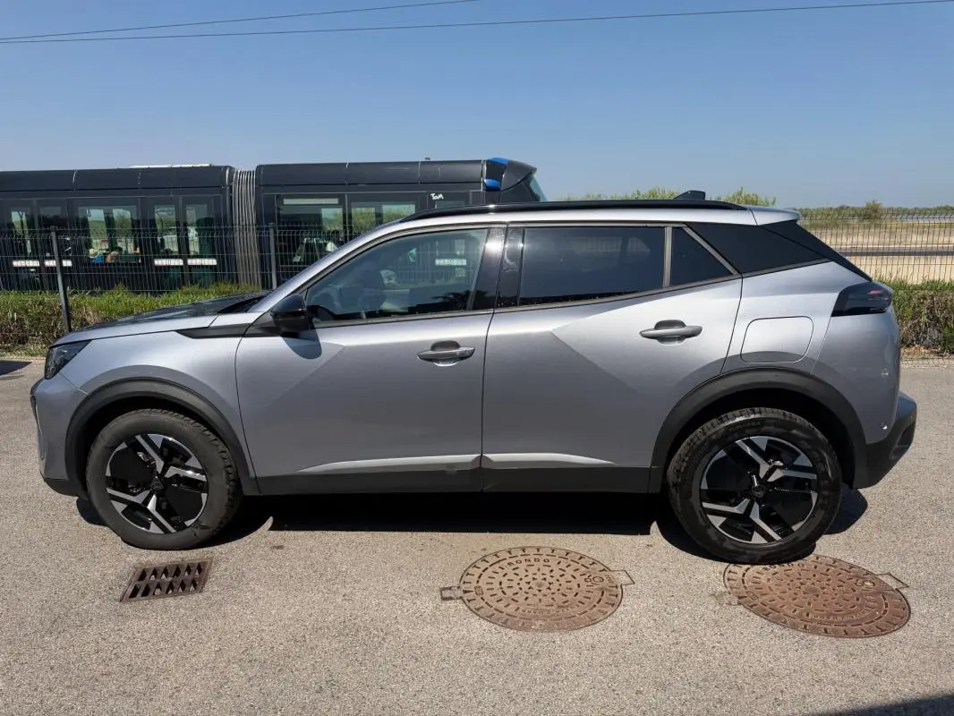 Vue latérale droite d’un Peugeot 2008 Hybrid 145 gris 2025, soulignant ses jantes noires et son design moderne.