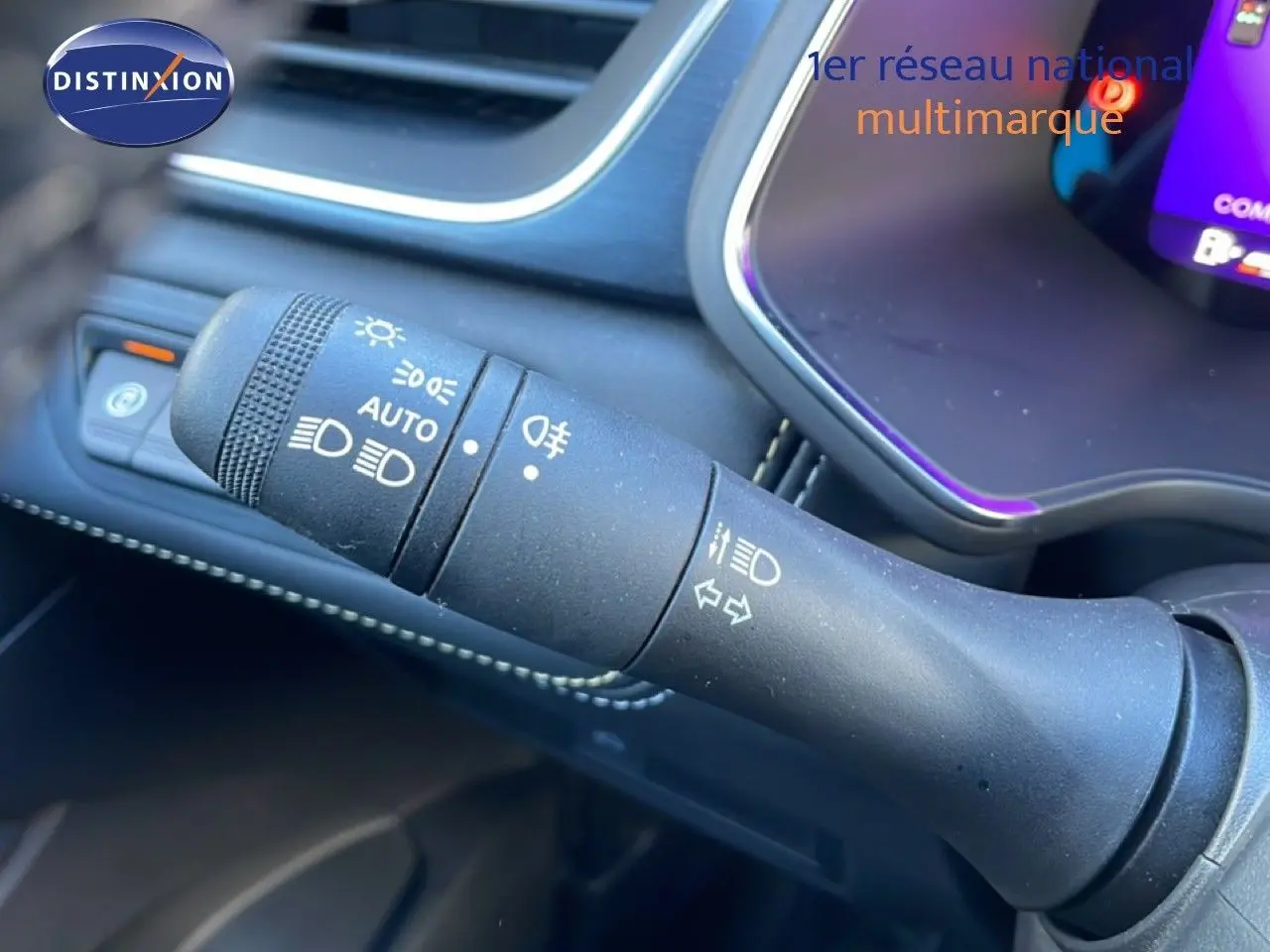 Gros plan sur la commande des phares et clignotants du tableau de bord intérieur d’une Renault Symbioz bleu iron metal.