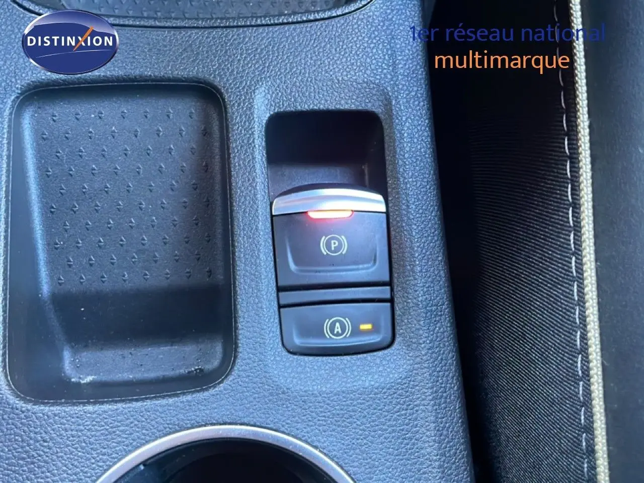 Gros plan sur la console centrale du Renault Symbioz 2025, avec boutons de frein à main et arrêt auto en plastique noir.