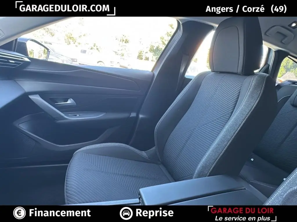 Vue intérieure côté passager avant de la Peugeot 308 gris clair avec sièges tissu et garnitures noires.