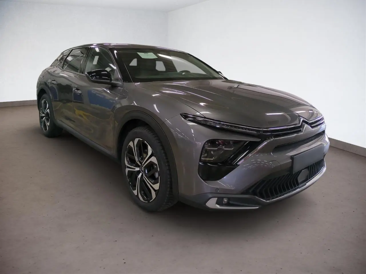 Vue 3/4 avant gauche d'une Citroën C5 X gris Platinium avec jantes alliage noires et signature lumineuse LED en V.