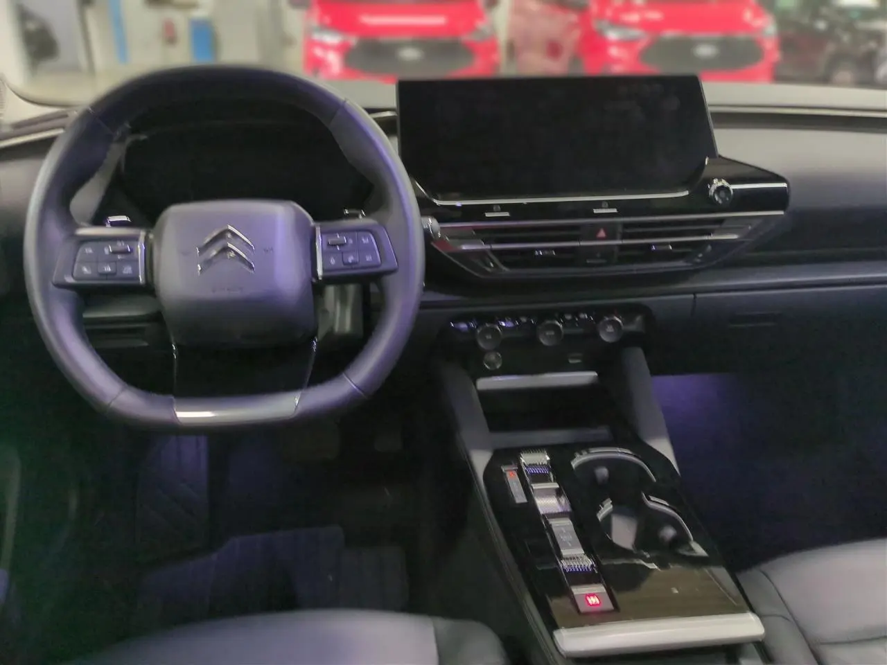 Vue intérieure avant centrée sur le volant cuir Citroën et l'écran tactile large du tableau de bord du C5 X Gris Platinium.
