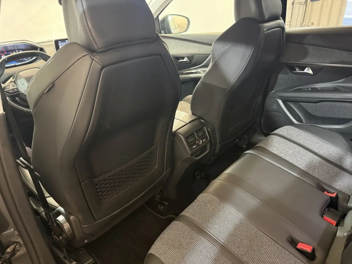 Vue intérieure arrière du Peugeot 3008 Puretech 130, sièges mixtes cuir et tissu gris, console centrale avec aérateurs.