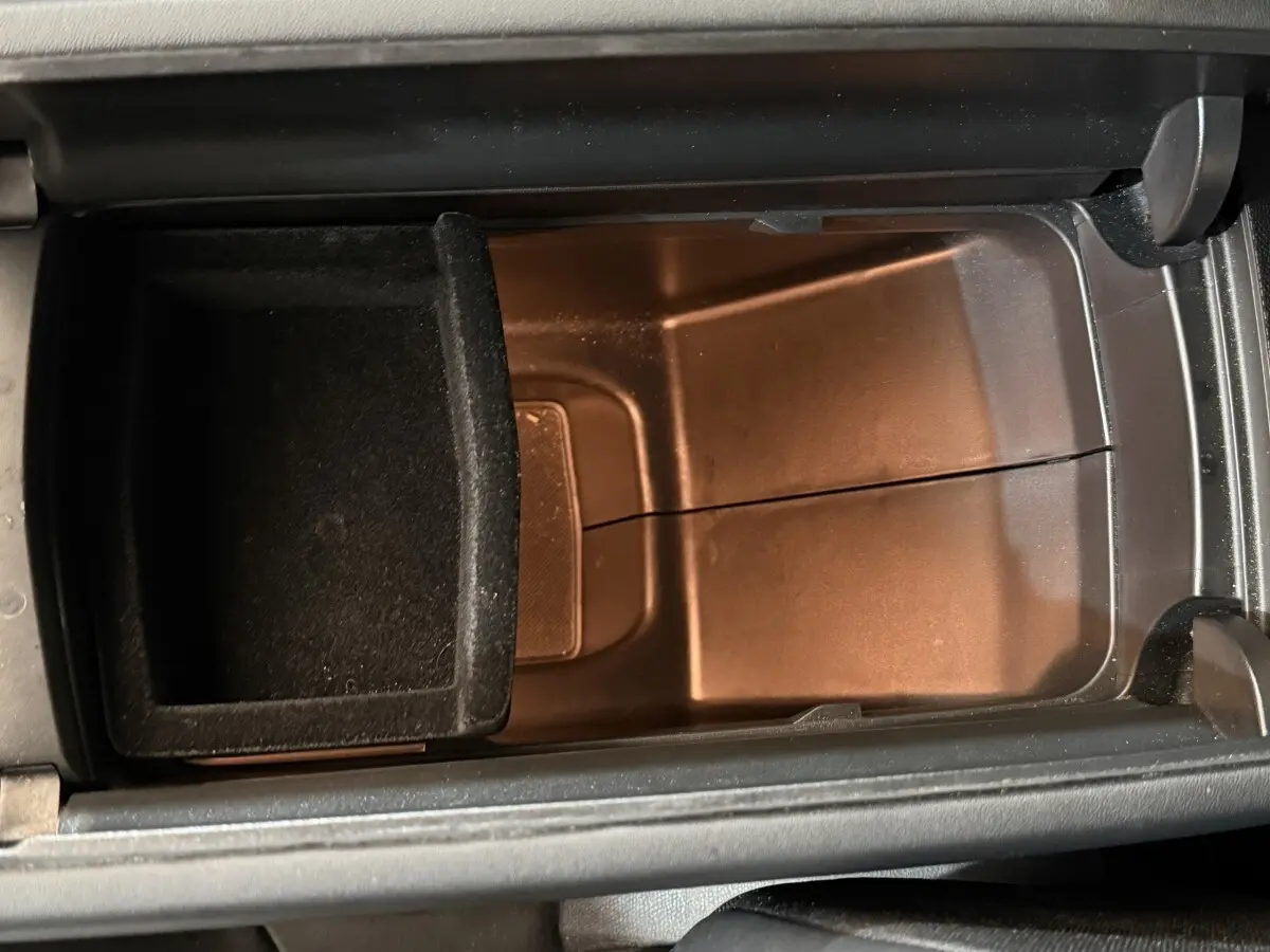 Vue rapprochée de la console centrale ouverte du Peugeot 3008, montrant un compartiment de rangement noir.