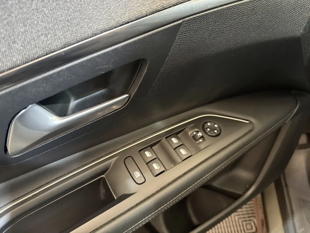 Gros plan sur la porte côté conducteur noire du Peugeot 3008 avec commandes électriques des vitres et poignée argentée.
