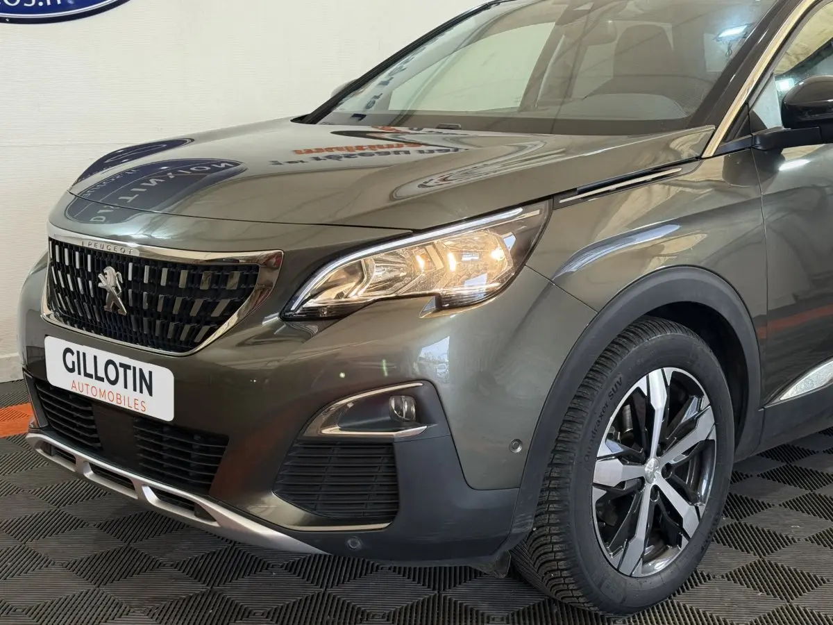 Vue 3/4 avant droit d’un Peugeot 3008 vert avec calandre noire et phares allumés dans un showroom.
