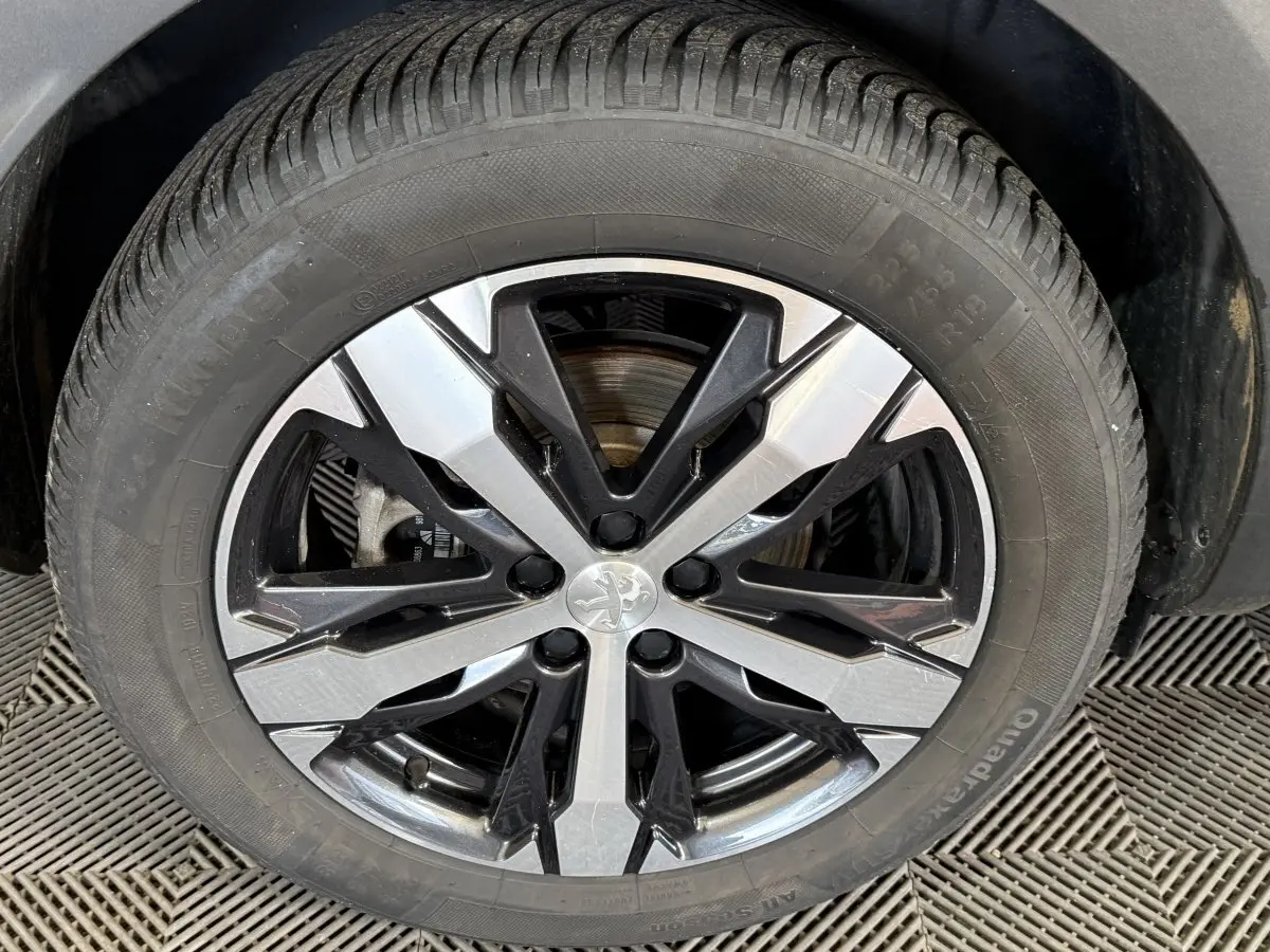 Gros plan sur la roue avant gauche d’un Peugeot 3008 vert, jante alliage bicolore noire et argentée.