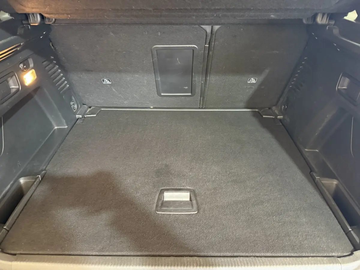 Coffre spacieux du Peugeot 3008 Puretech 130 vert, vue intérieure avec banquette arrière rabattue et éclairage latéral.
