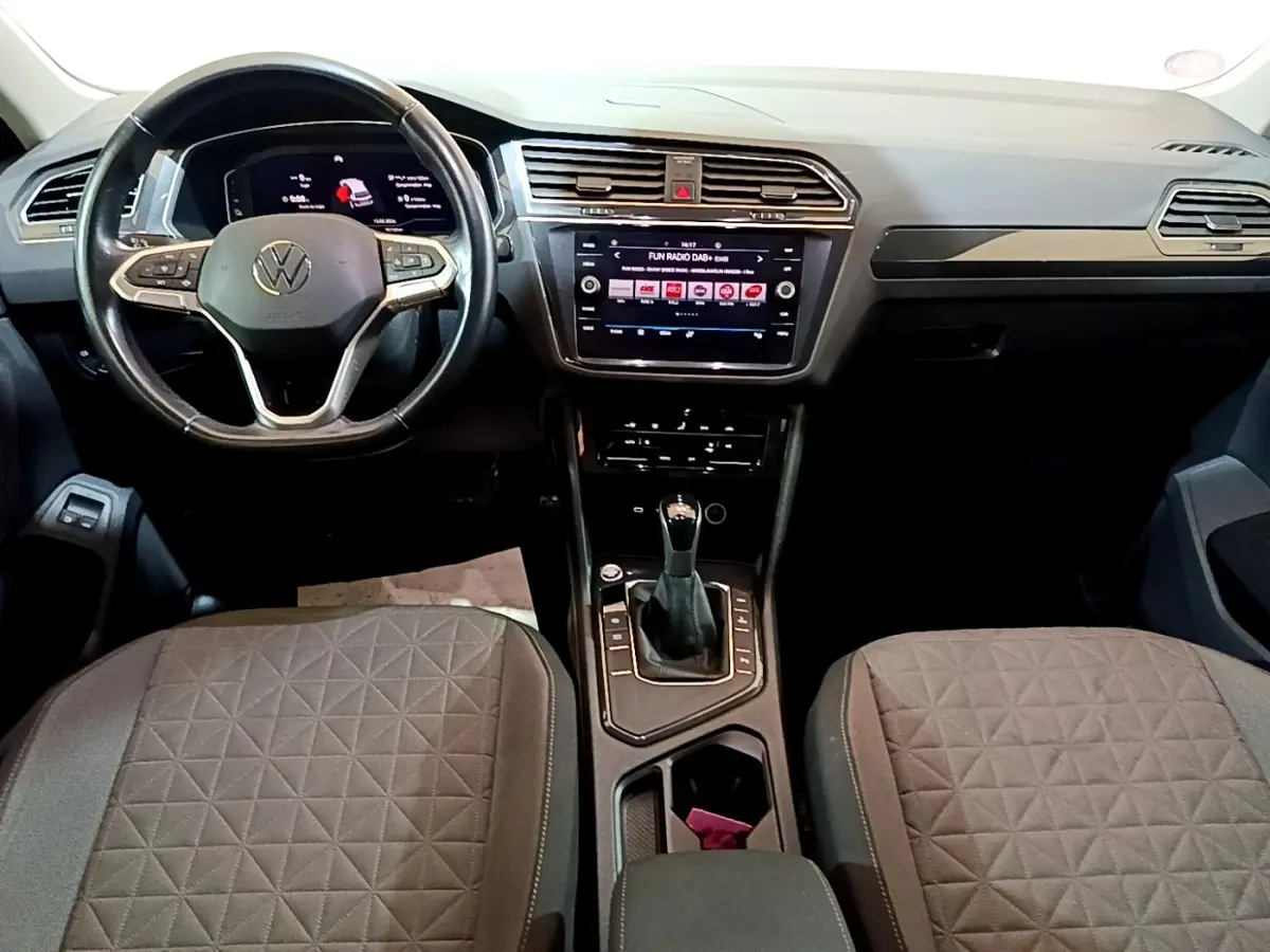 Vue intérieure du tableau de bord et console centrale du Volkswagen Tiguan 1.4 eHybrid, avec volant cuir et écran tactile.