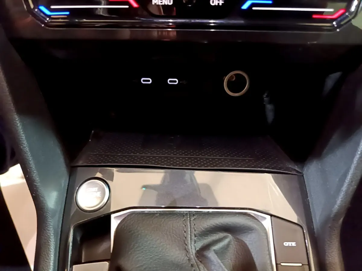 Gros plan sur la console centrale du Volkswagen Tiguan bleu, avec bouton démarrage et levier de vitesse en cuir.