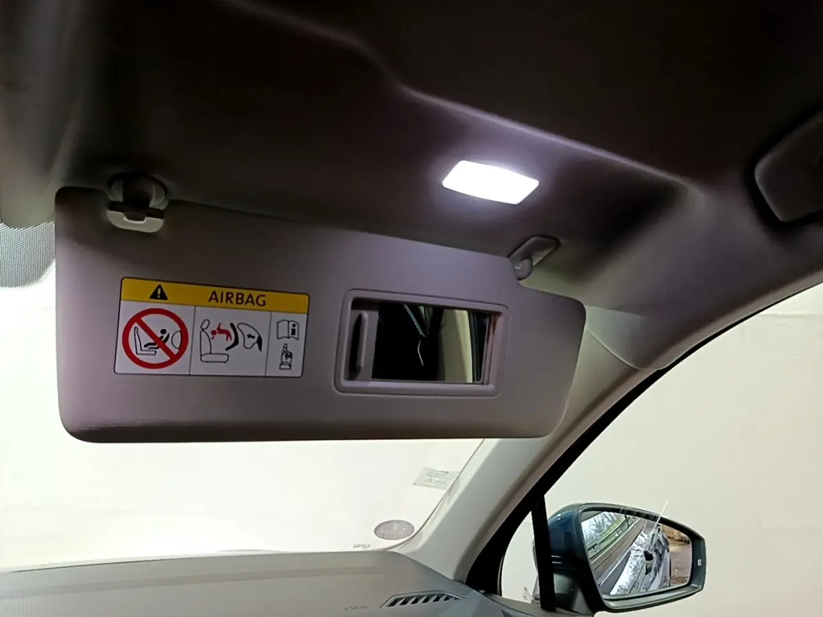 Détail du pare-soleil côté conducteur avec miroir intégré et rétroviseur extérieur bleu du Volkswagen Tiguan 1.4 eHybrid.