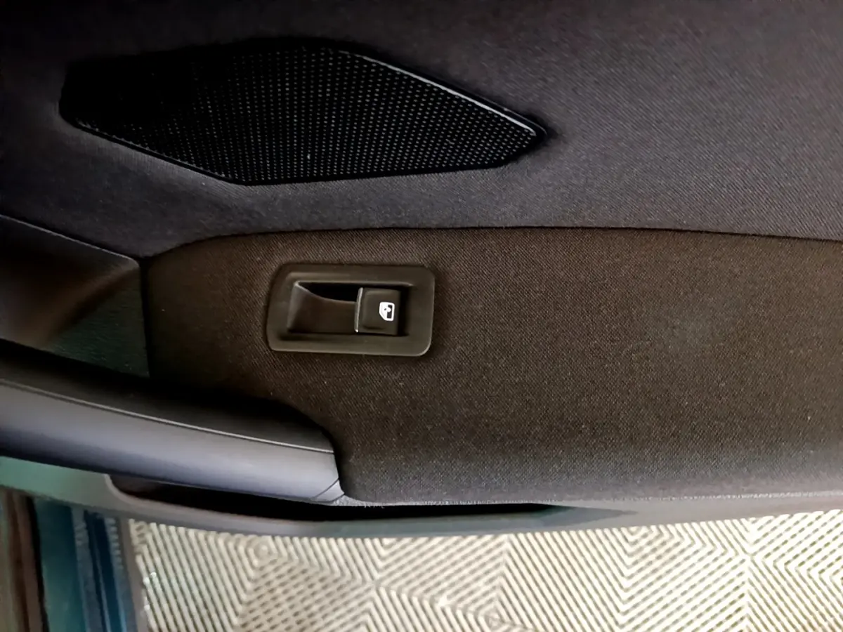 Détail de la porte intérieure côté conducteur du Volkswagen Tiguan bleu, avec bouton de verrouillage centralisé.