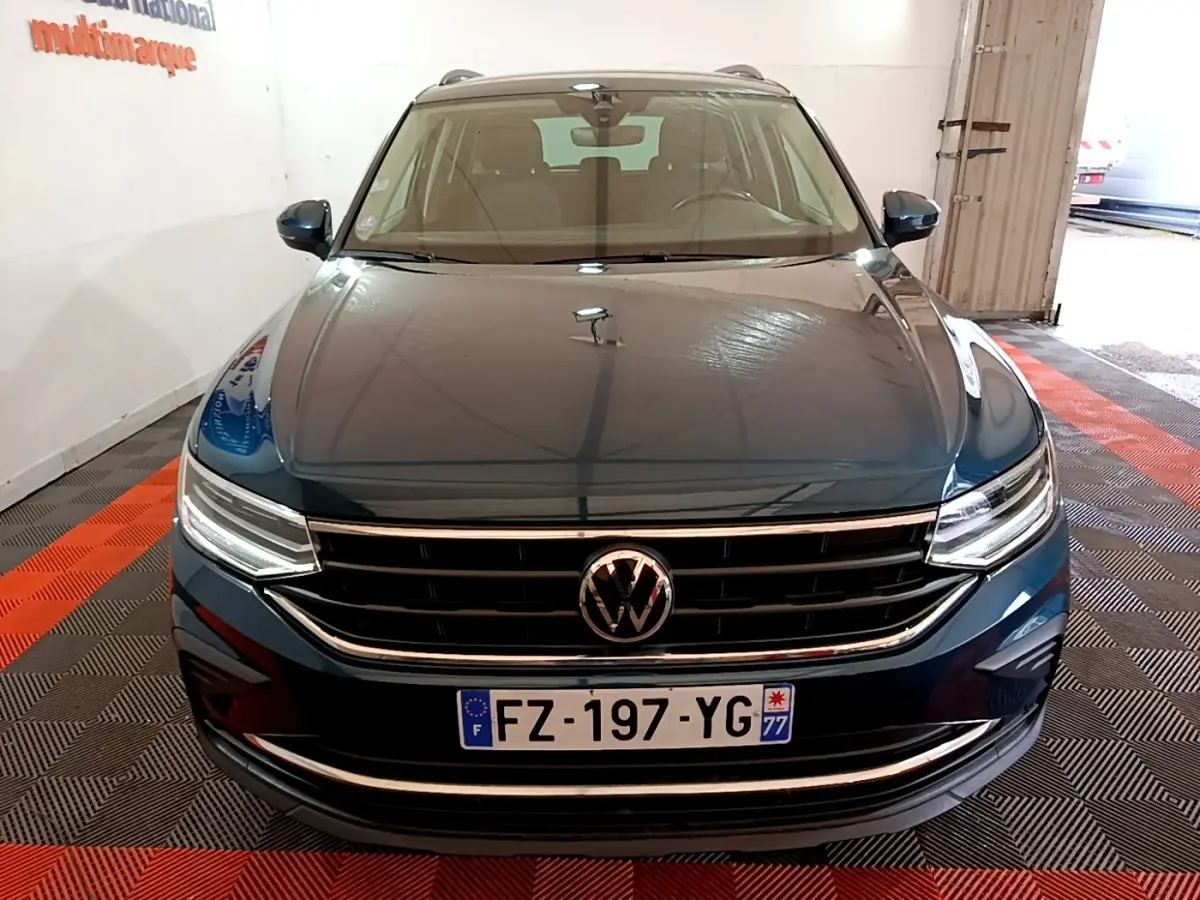Vue avant d'un Volkswagen Tiguan bleu 1.4 eHybrid 245 DSG6 Life Business dans un garage lumineux.