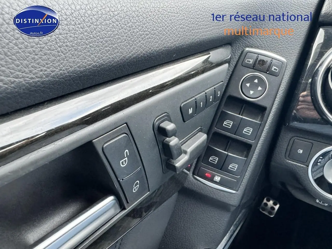 Détail intérieur montrant les commandes des vitres et rétroviseurs côté conducteur d’une Mercedes GLK noire 2014.