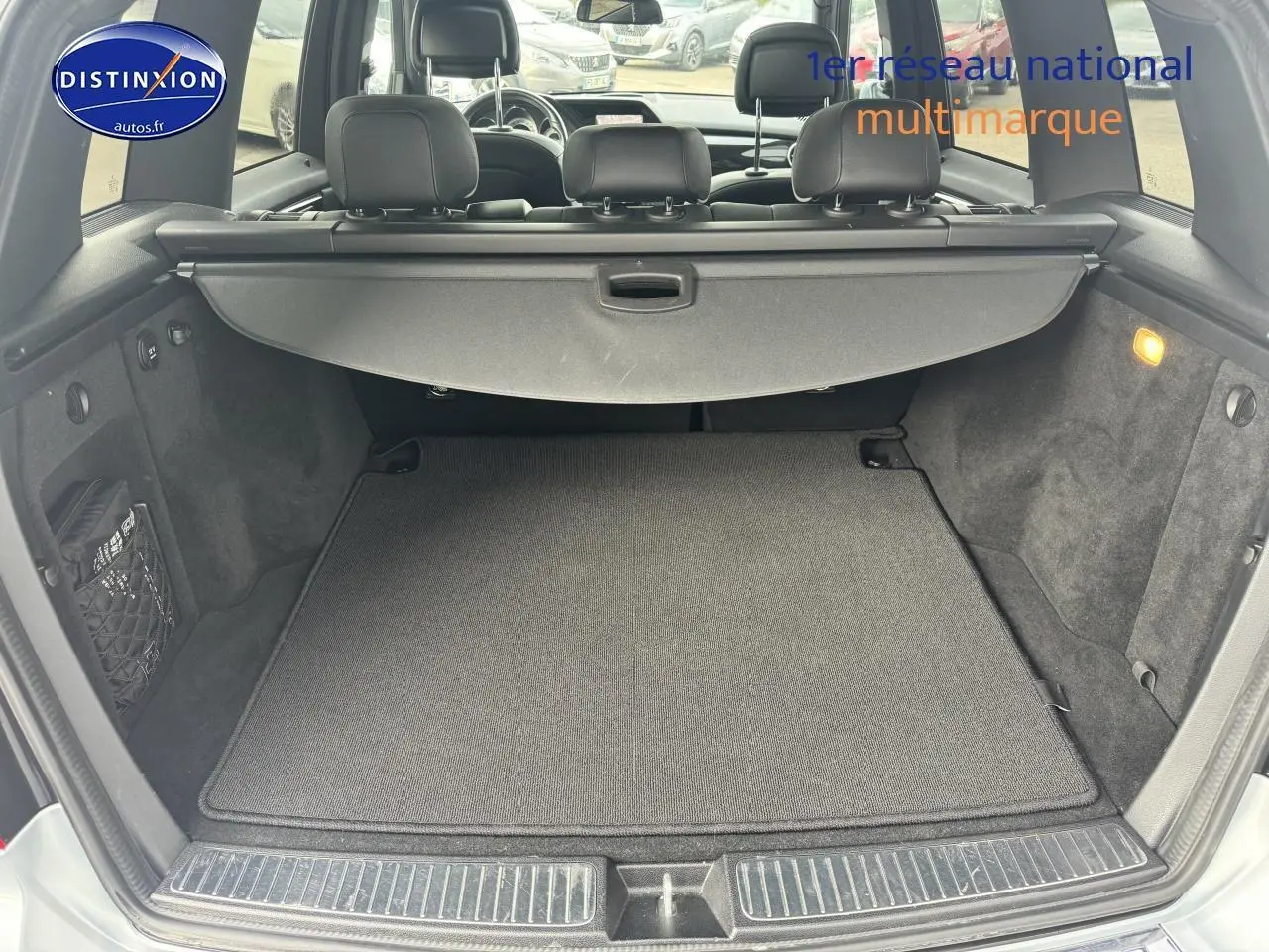 Coffre ouvert d’un Mercedes GLK noir, montrant la tablette cache-bagages et l’espace de chargement vide.