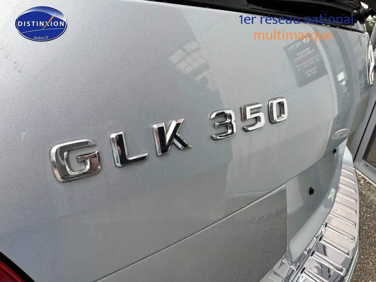 Gros plan sur le logo GLK 350 en chrome sur la porte arrière d’un Mercedes noir, avec marchepied visible.