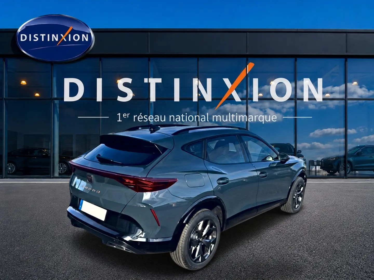 Vue 3/4 arrière droite d'un CUPRA Formentor bleu fjord avec jantes noires devant une vitrine Distinxion.