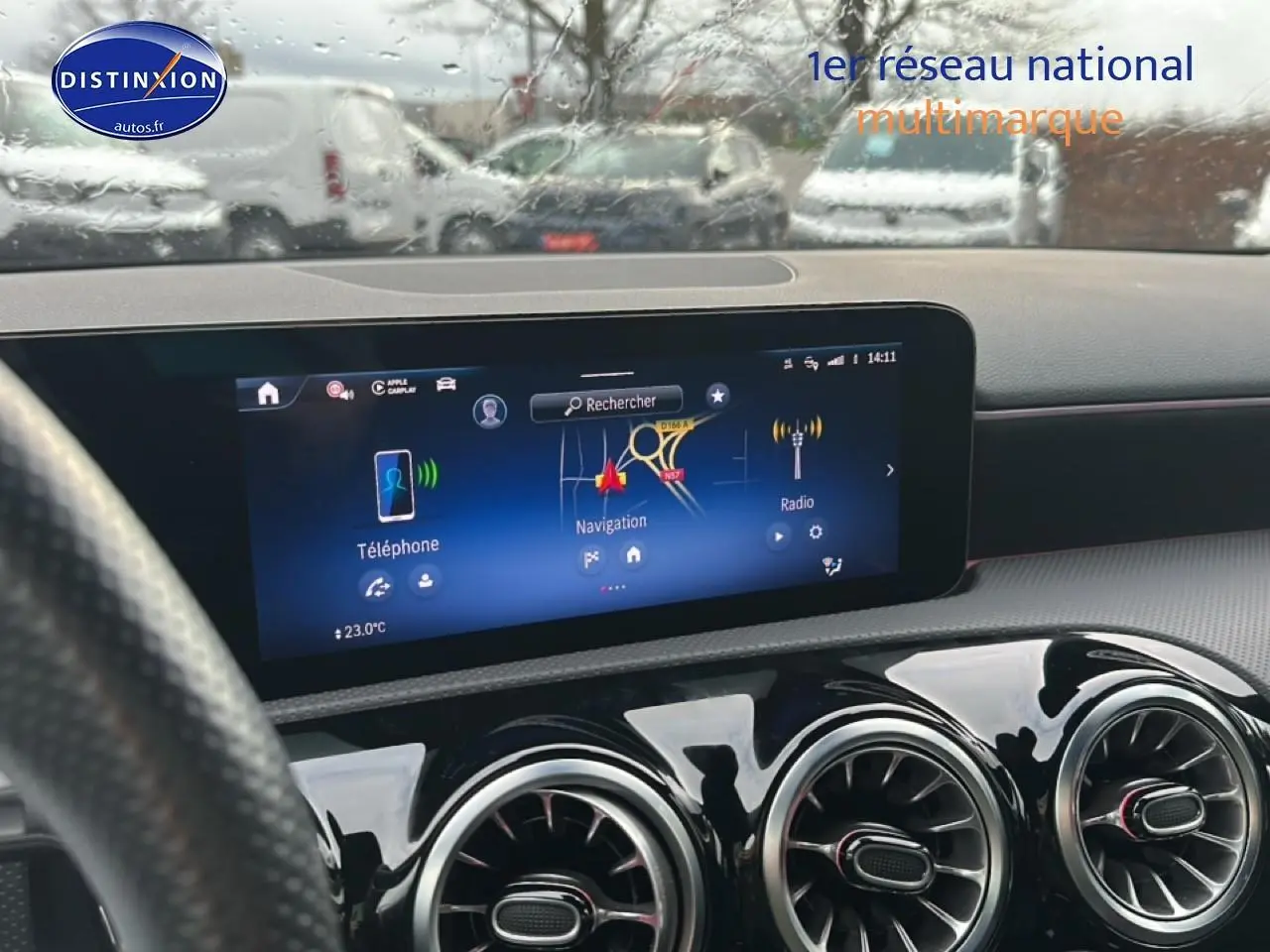 Vue intérieure centrée sur l'écran tactile et les aérateurs ronds du tableau de bord d'une Mercedes Classe A 180 AMG Line bleu.