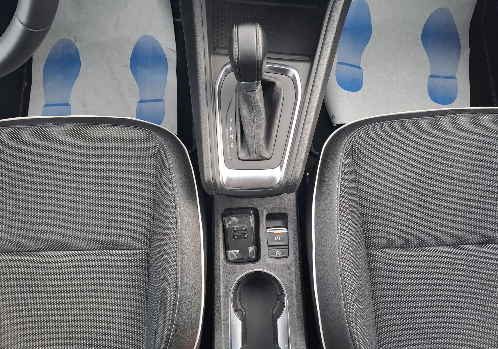 Vue plongeante sur la console centrale du Renault Captur gris cassiopée, avec levier de vitesse automatique et sièges tissu noirs.