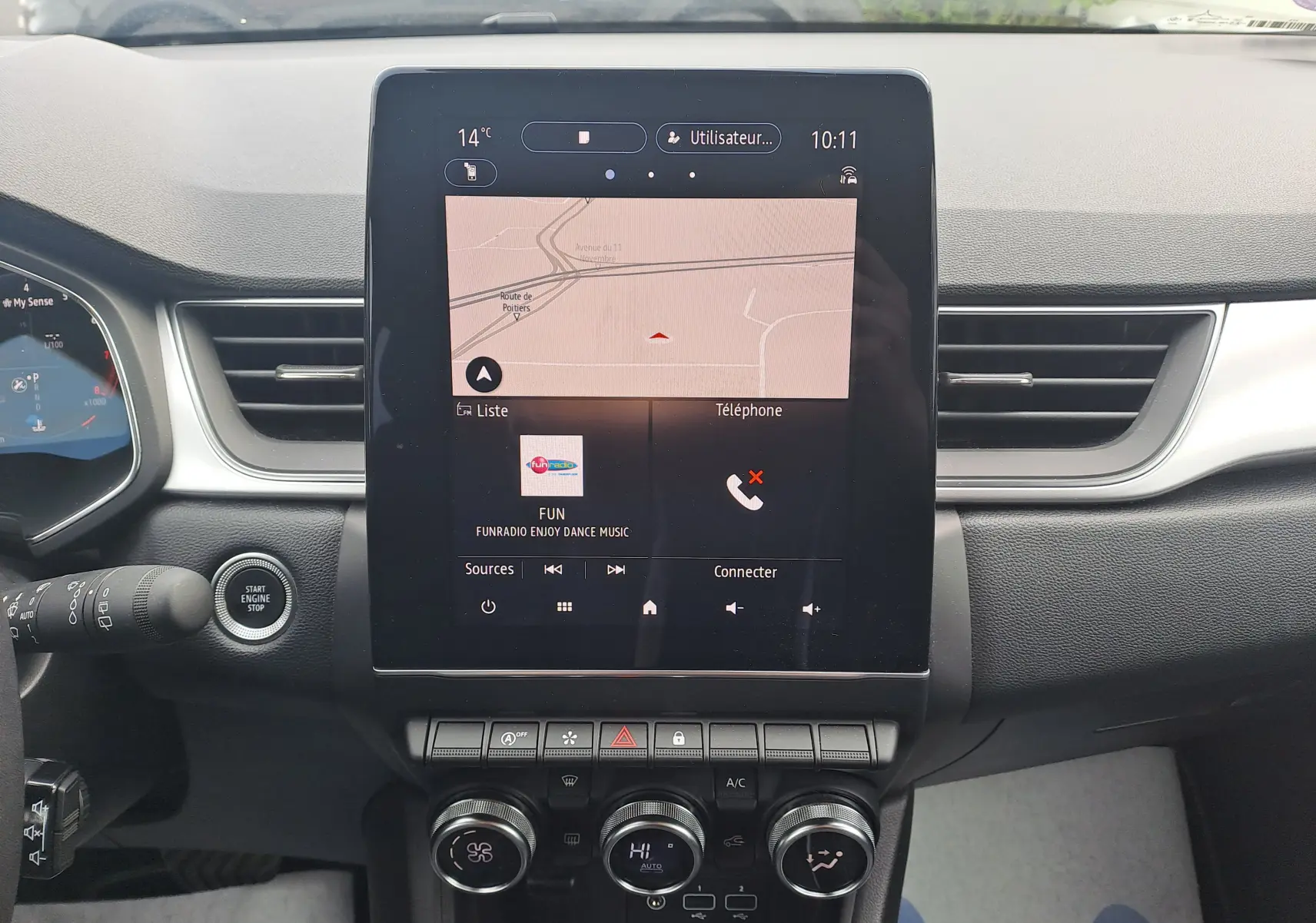 Vue intérieure centrée sur l'écran tactile du tableau de bord du Renault Captur gris Cassiopée avec toit noir, affichant la navigation et la radio.