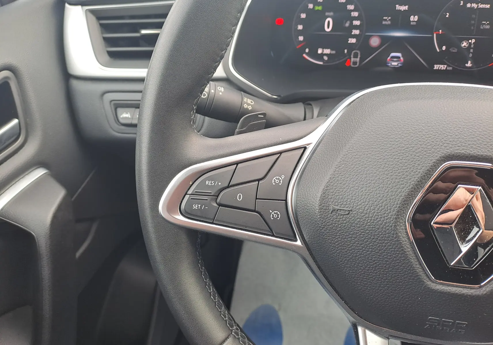 Gros plan sur le volant noir de la Renault Captur 2022 avec commandes intégrées et tableau de bord numérique en arrière-plan.