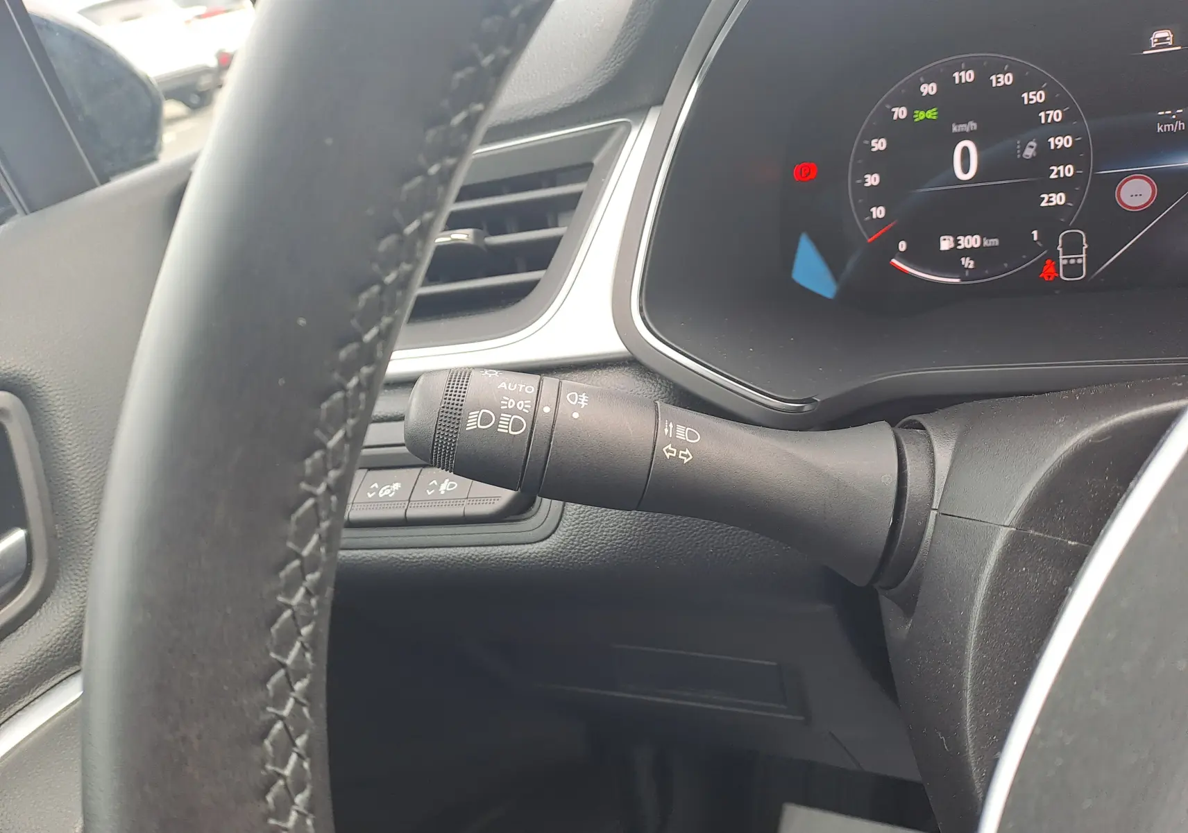 Gros plan sur la commande des phares et clignotants à gauche du volant dans l'habitacle du Renault Captur gris cassiopée.