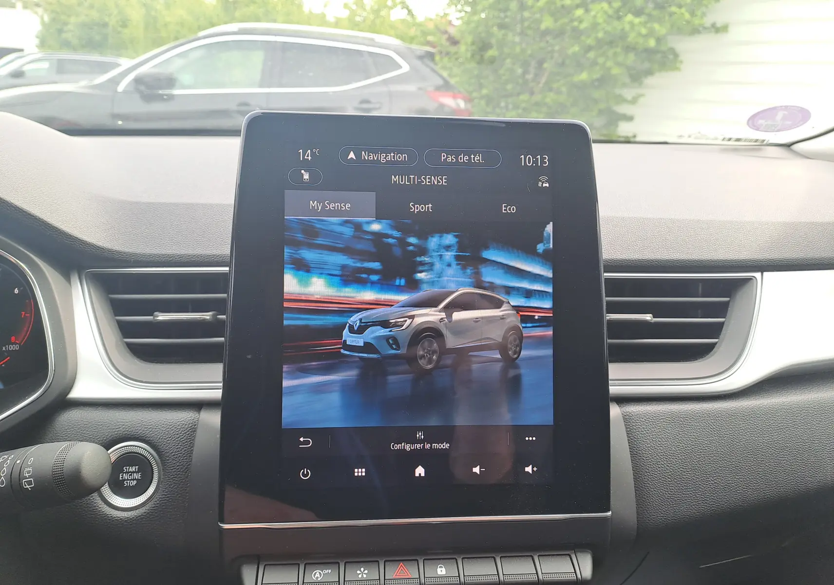 Écran central affichant une Renault Captur gris Cassiopée avec toit noir en vue 3/4 avant dynamique.