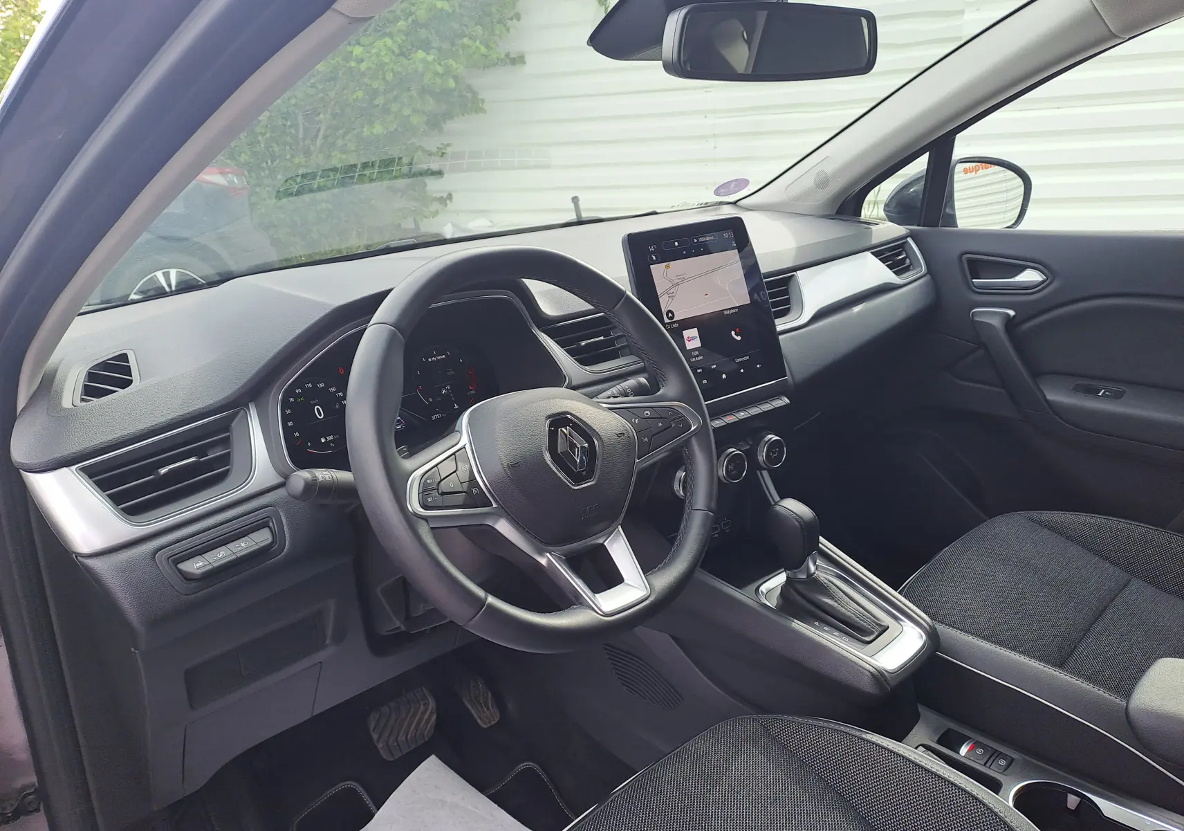 Vue intérieure côté conducteur du Renault Captur 2022, tableau de bord noir avec écran tactile vertical et volant multifonction.