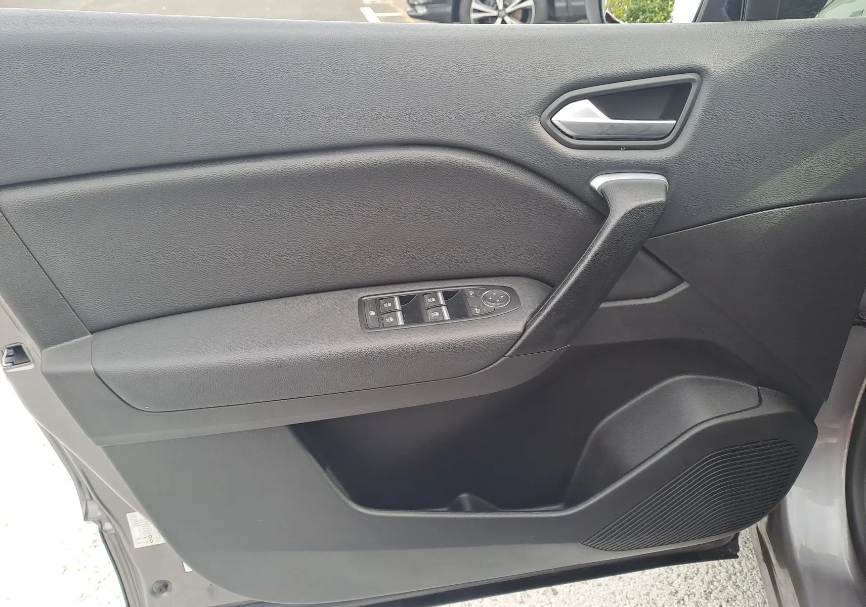 Vue intérieure du panneau de porte avant gauche du Renault Captur 2022 gris cassiopée avec commandes électriques et poignée noire.