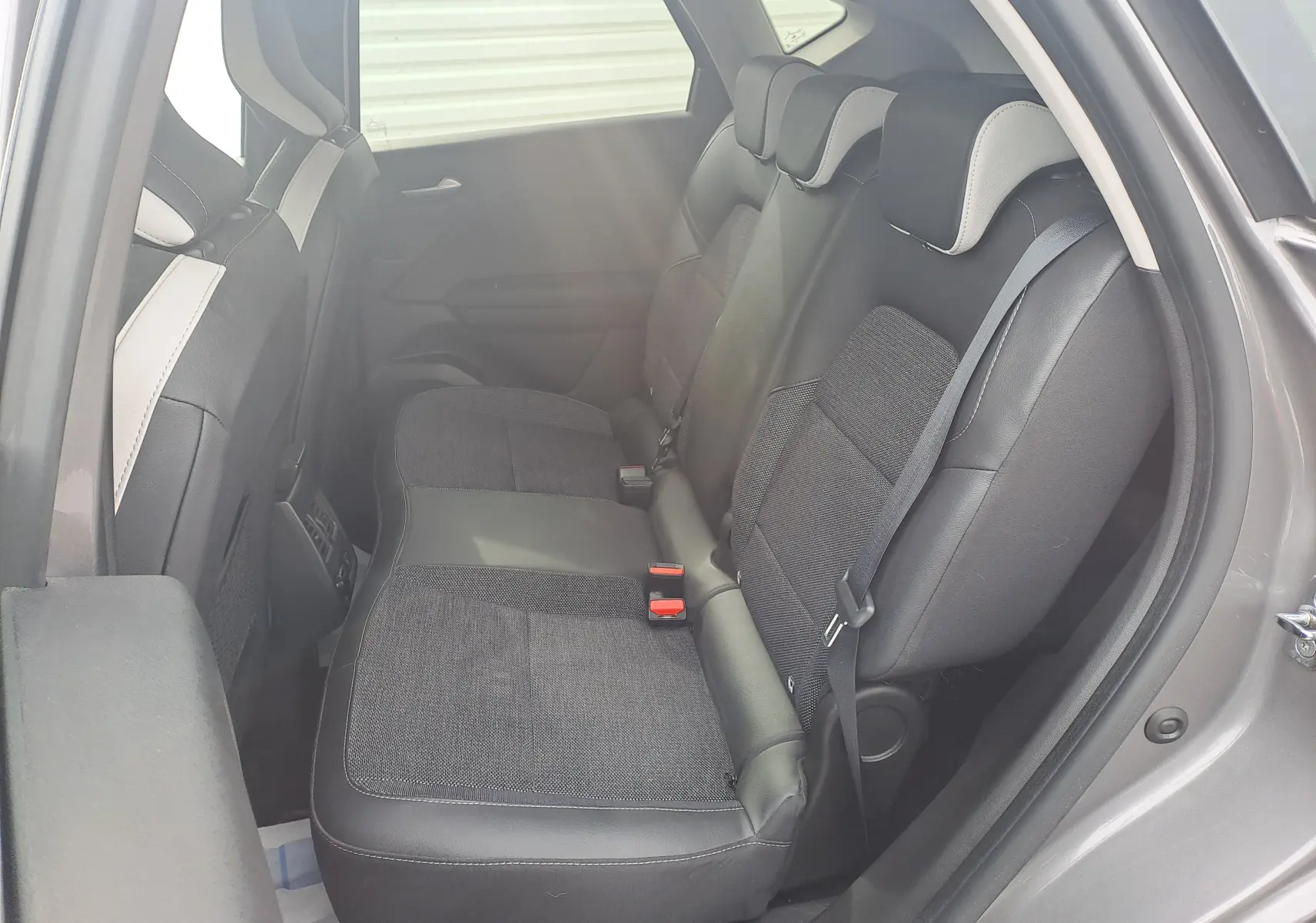 Vue intérieure côté droit des sièges arrière en tissu et cuir noir du Renault Captur gris Cassiopée 2022.