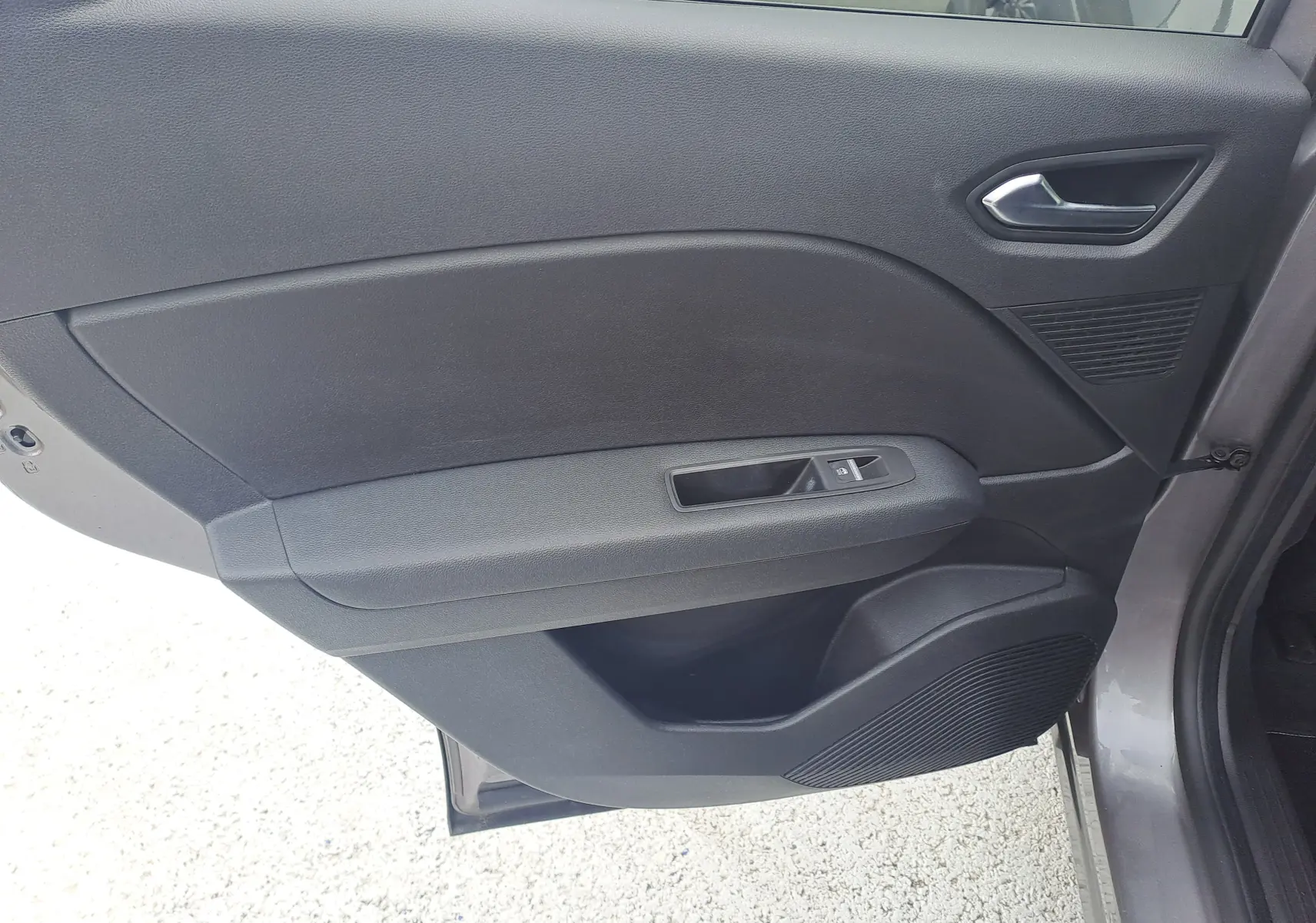 Vue intérieure de la porte arrière droite du Renault Captur gris Cassiopée avec poignée et commande de vitre noire.