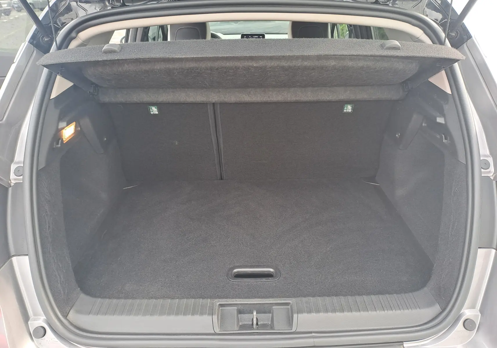 Coffre ouvert vu de l'arrière du Renault Captur gris Cassiopée avec toit noir, montrant l'espace de chargement vide et le cache-bagages relevé.
