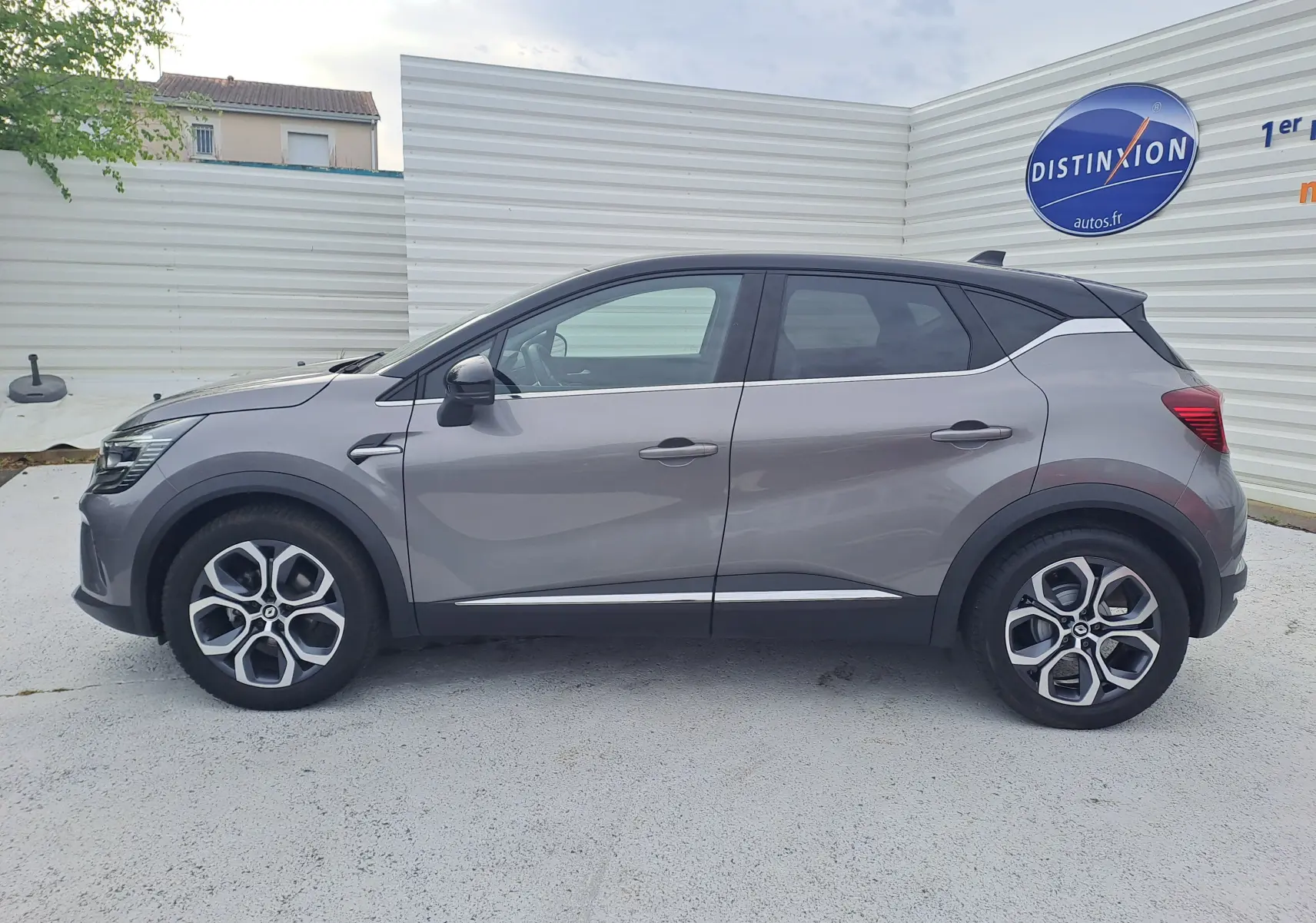 Profil gauche d'un Renault Captur gris Cassiopée avec toit noir, roues alliage et lignes de carrosserie marquées.
