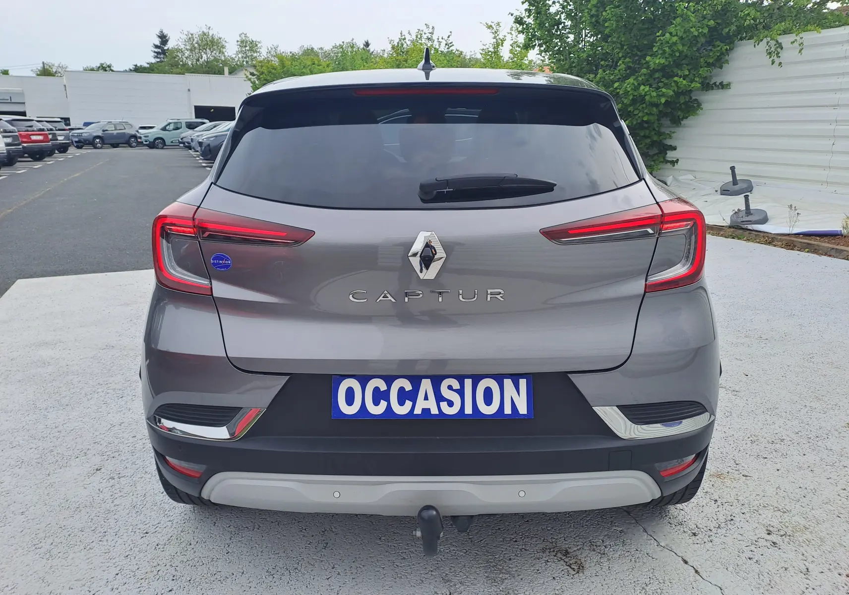 Vue arrière d’un Renault Captur gris Cassiopée avec toit noir, feux LED et attelage visible sur parking.