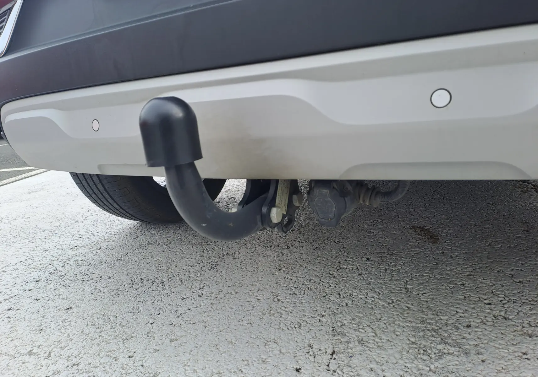 Gros plan sur l'attelage noir sous le pare-chocs arrière gris cassiopée du Renault Captur 2022.