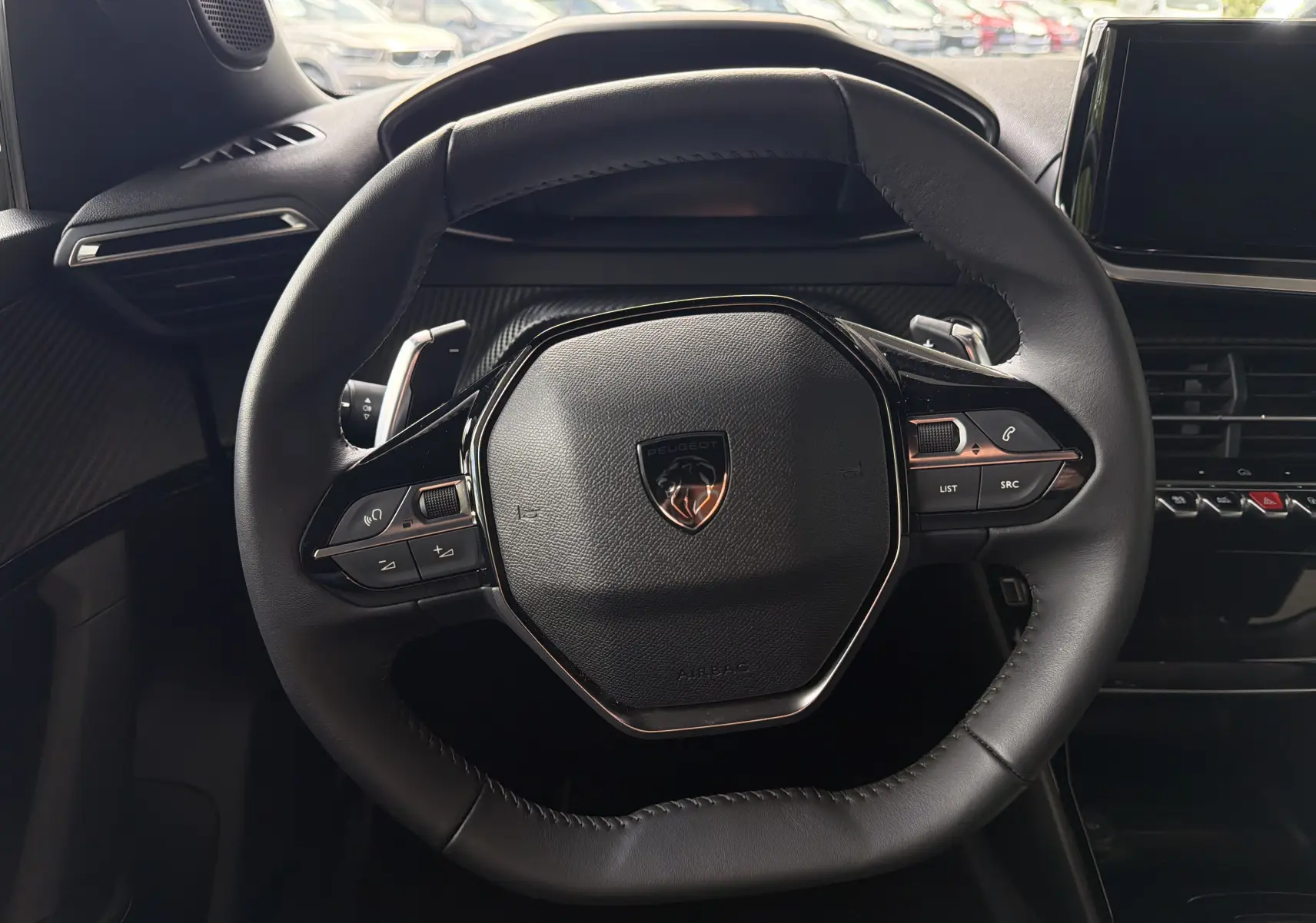 Vue rapprochée du volant cuir noir du Peugeot 2008 1.2 130 EAT8 Allure 2023, avec commandes intégrées et logo central.