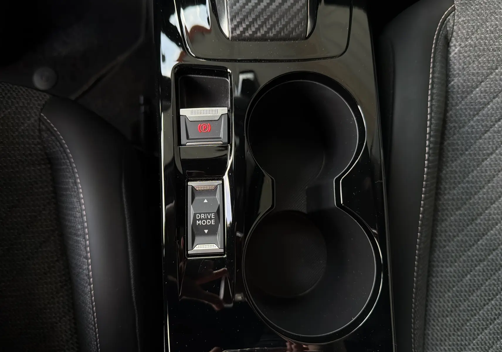 Vue plongeante sur la console centrale noire brillante du Peugeot 2008 avec boutons frein à main électronique et mode de conduite.