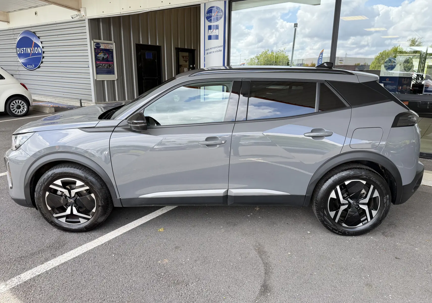 Profil côté gauche du Peugeot 2008 gris Sellenium 2023, avec jantes bi-ton et toit noir contrasté.
