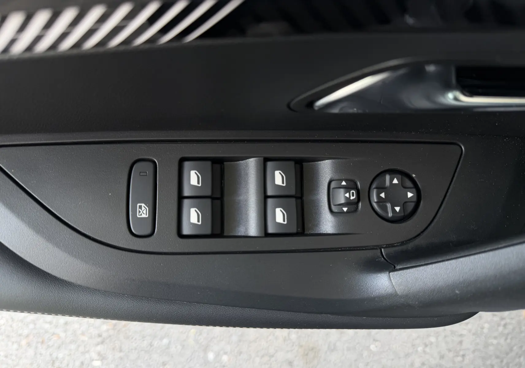 Vue rapprochée des commandes de lève-vitres et réglage des rétroviseurs côté conducteur d’un Peugeot 2008 gris Sellenium.