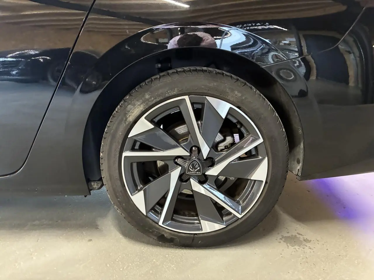 Gros plan sur la roue arrière droite d’une Peugeot 308 SW noire avec jante alliage 17'' au design géométrique.