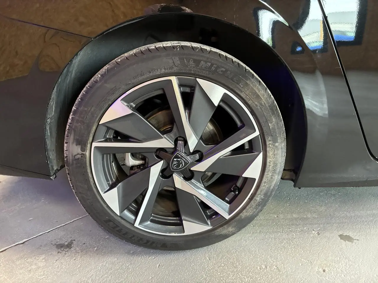 Gros plan sur la jante alliage 17'' Halong diamantée noire et argentée du côté arrière droit d'une Peugeot 308 SW noire.
