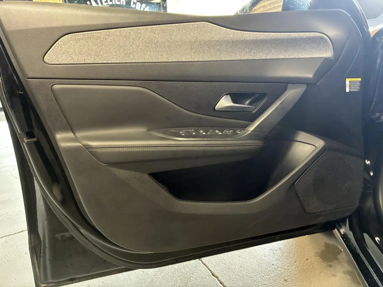 Porte avant gauche noire de la Peugeot 308 SW 2024 avec commandes de vitres et haut-parleur intégré.