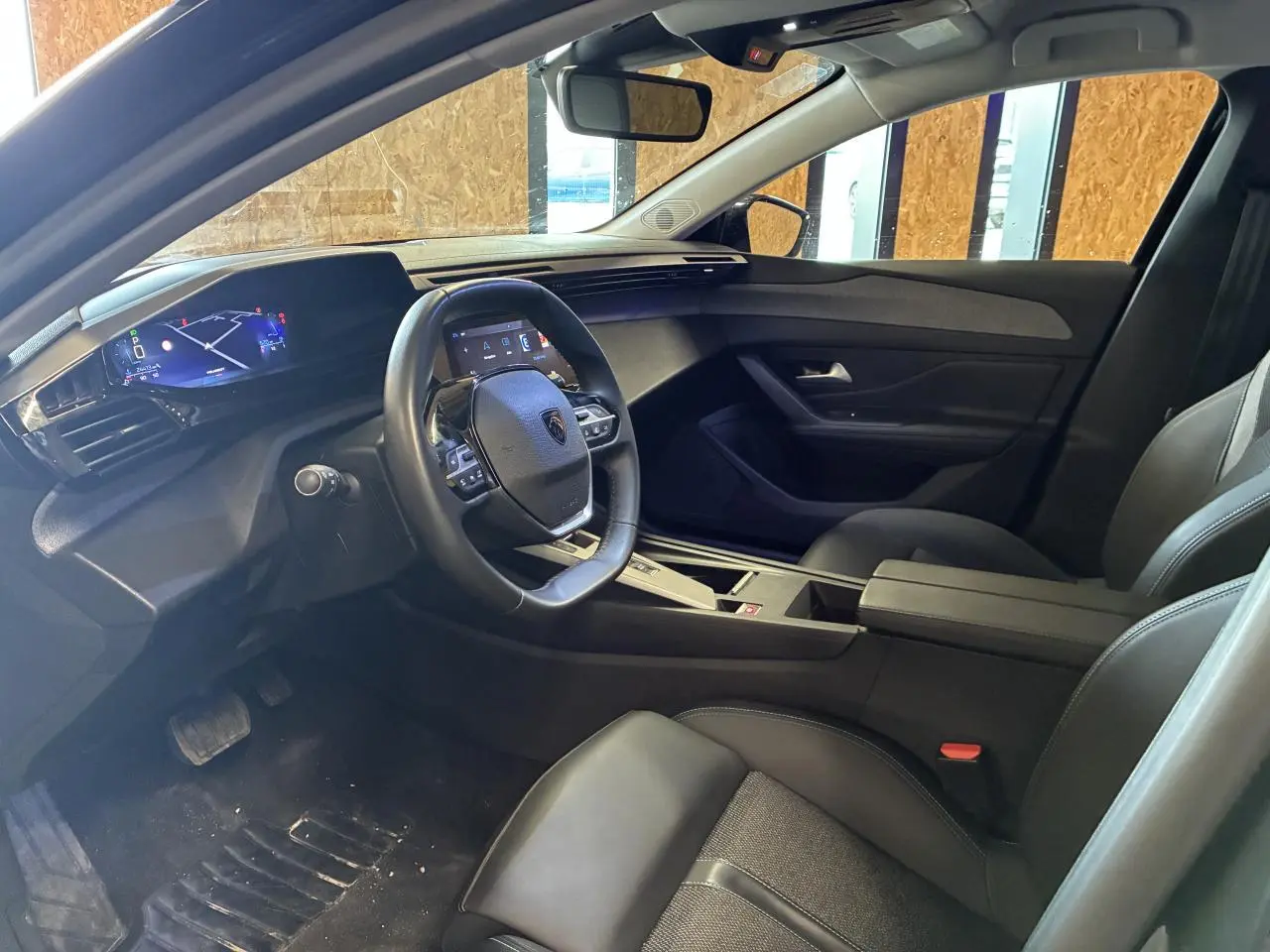 Intérieur Peugeot 308 SW 2024 vu côté conducteur, tableau de bord numérique et sellerie noire moderne.